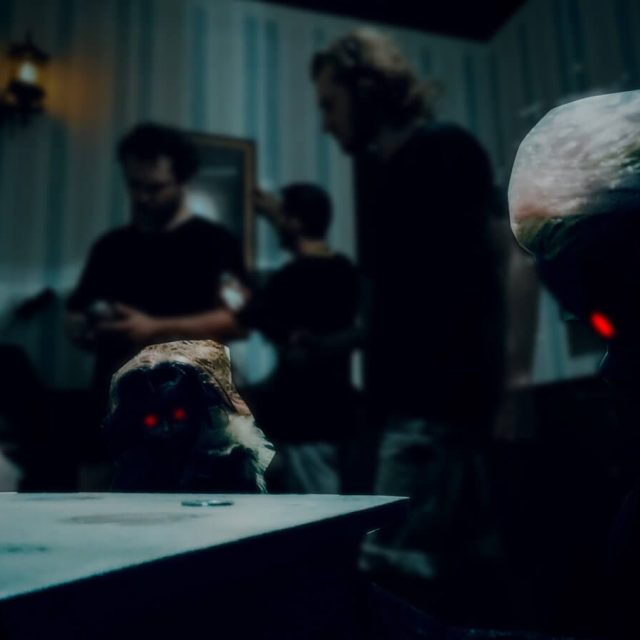 Joueurs en silhouette autour d'une table, tête de statue aux yeux rouges, salle Le manoir sinistre chez Freeing à Saint-Maximin