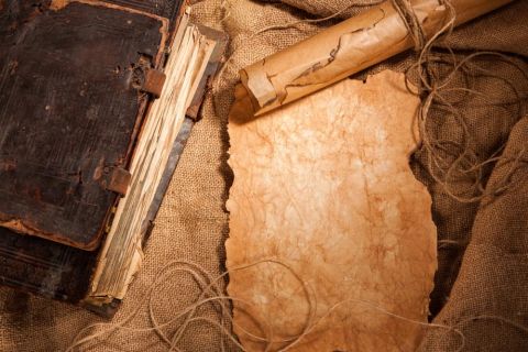 Vieux livre relié, parchemin enroulé et papier vierge sur toile de jute, salle Le secret de Léonard de Vinci à Pornichet