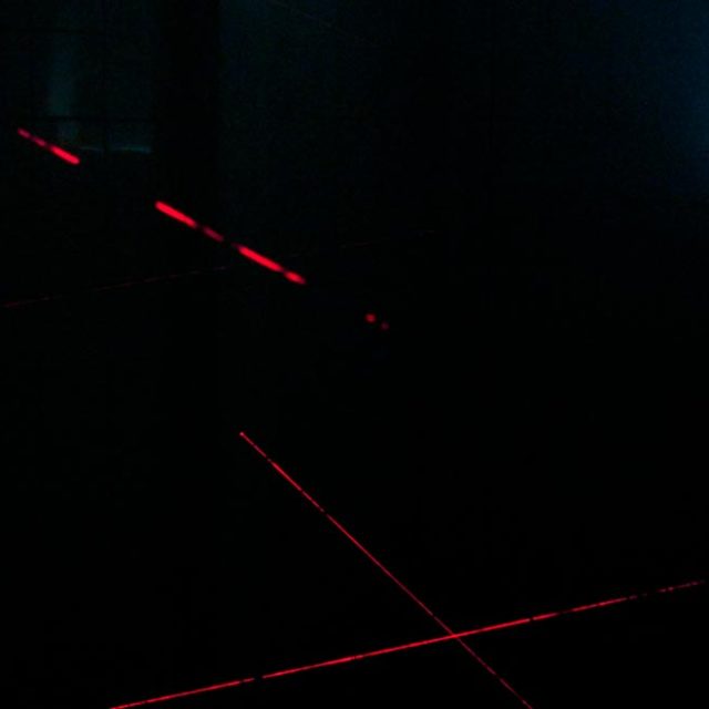 Salle sombre avec lasers rouges et écran bleu dans Time Lab à Barjouville