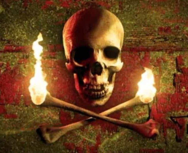 Crâne flanqué de torches enflammées et d'os croisés, décor pirate du Vaisseau Fantôme chez Clock escape à Bordeaux