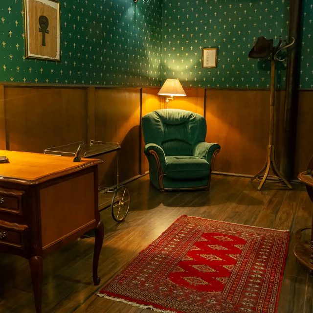 Bureau années 1930 avec fauteuil vert, bureau bois, globe terrestre et papiers dans L'inquiétant professeur Tychsen
