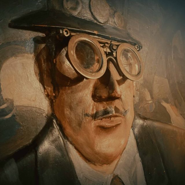 Portrait peint d'un homme moustachu portant lunettes de soudeur et casquette, salle Sherlock à Les Pennes-Mirabeau