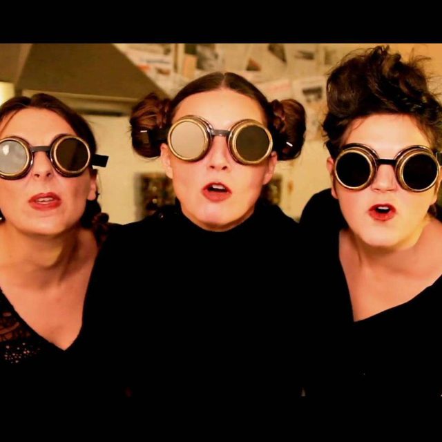 Trois personnes en tenue noire portant des lunettes steampunk dans un décor industriel chez Lock Busters Paris