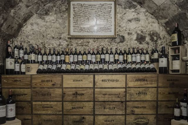 Cave voûtée en pierre avec casiers de bouteilles de vin alignés, salle In Vino Veritas chez La Clef à Bergerac