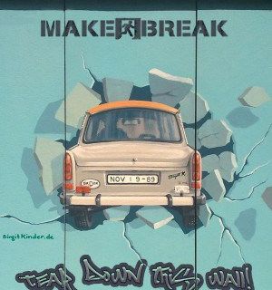 Voiture vintage écrasant un mur de briques bleues, logo de Make a Break Berlin