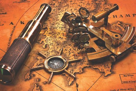 Longue-vue en laiton, compas et sextant posés sur une vieille carte orange, salle Capitaine Flint Freaky chez Double Tour