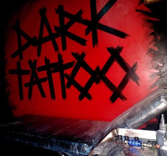 Mur rouge sang avec symboles noirs et objets métalliques dans Dark Tattoo