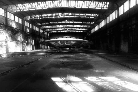 Vaste hangar industriel en noir et blanc avec soucoupe volante au plafond, salle La Zone 51, The four gates à Soissons