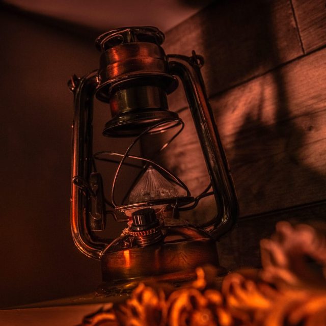 Lanterne ancienne éclairée à la lueur orange dans une ambiance de navire pirate