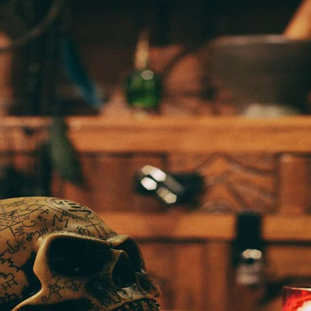 Crâne et flacons sur un établi en bois sombre, salle Vaudou chez Escape Yourself à Poitiers
