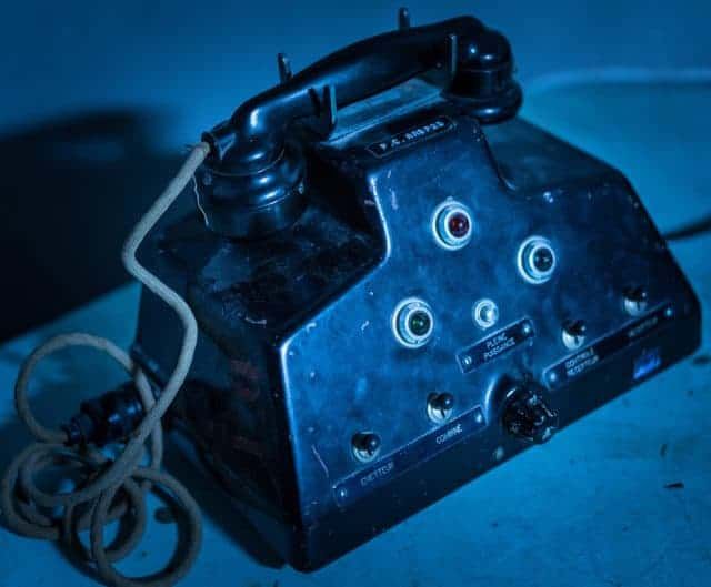 Ancien téléphone de campagne aux prises rondes sur fond bleu, salle Power Station chez Hydre Aventures à Lyon