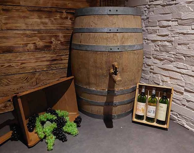 Tonneau de vin, bouteilles et raisin dans la salle Opération Saint-Émilion