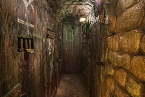 Couloir souterrain aux murs de bois pourri et pierre, éclairage tamisé, dans Escape the Kingdom