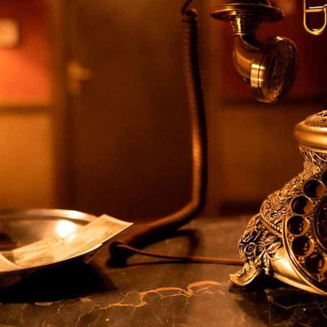 Téléphone ancien à cadran, billet posé sur une coupelle et lampe, salle Sunhill Hotel chez Escape Time à Laval