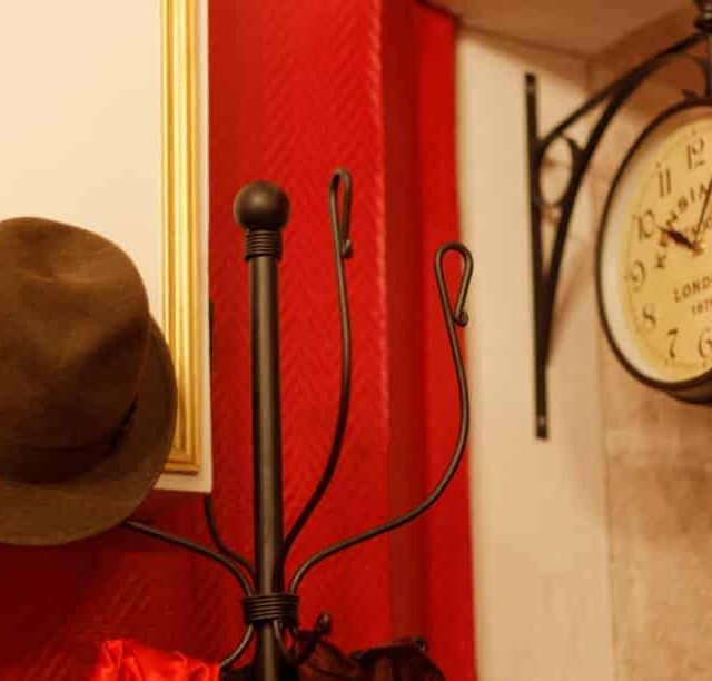 Décor vintage du Bureau d'Irène Adler : chapeau, horloge murale, accessoires enquête chez 221B Baker Street à Dijon