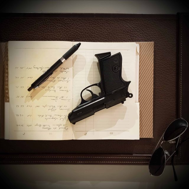 Pistolet, stylo plume et lunettes sur un cahier manuscrit ouvert, salle Opération Balkans, Quest Factory à Paris