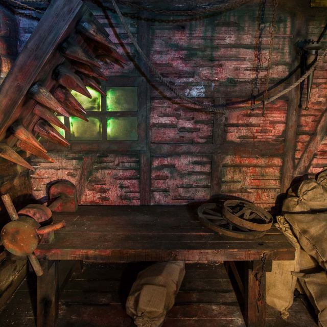 Grenier délabré aux murs de briques rouges, table en bois et objets anciens rouillés dans Escape the Kingdom