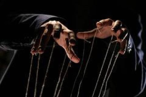 Marionnettes manipulées par des fils dans l'obscurité, ambiance sinistre dans la salle Le Marionnettiste