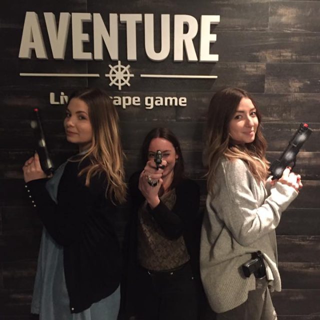 Trois joueurs posent avec des accessoires devant le logo d'Aventure Live! Escape Game à Nice