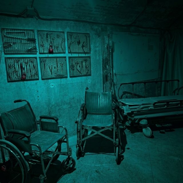 Salle d'asile abandonnée aux murs délabérés, fauteuils roulants et lits métalliques