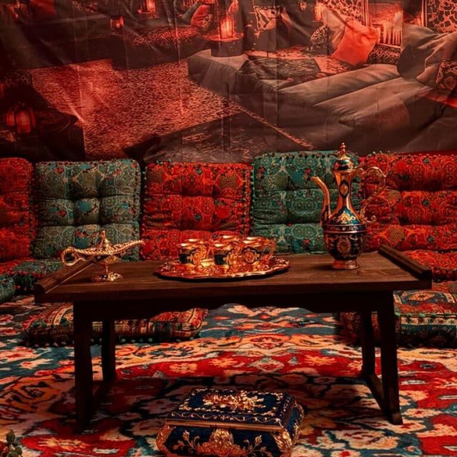 Salon oriental aux coussins verts et tapis rouges autour d'une table basse, salle La lampe magique chez Fun Room à Lons