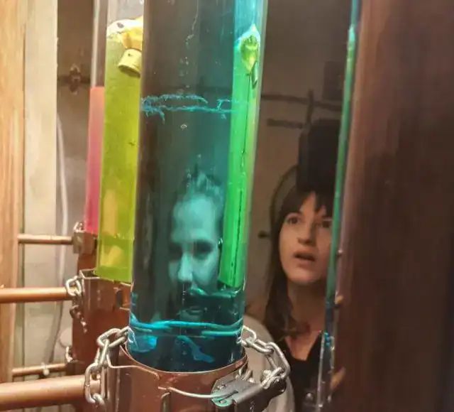 Joueuse derrière un tube de liquide coloré enchaîné, salle Les fabuleuses inventions du docteur Apfelglück à Saint-Jeoire-Prieuré