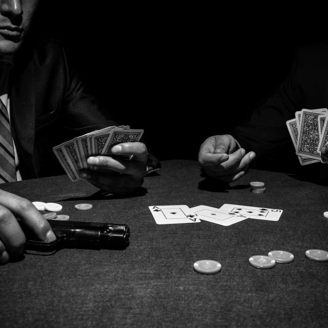 Deux hommes en costume jouent au poker autour d'une table noire dans Mamma Mafia chez A Maze In à Strasbourg