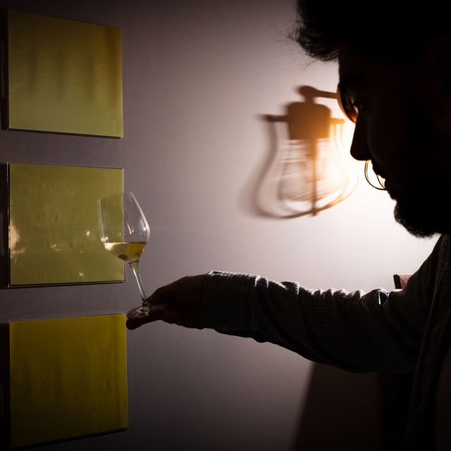 Silhouette devant des panneaux jaunes tenant un verre de vin, lanterne allumée au Château de Luc