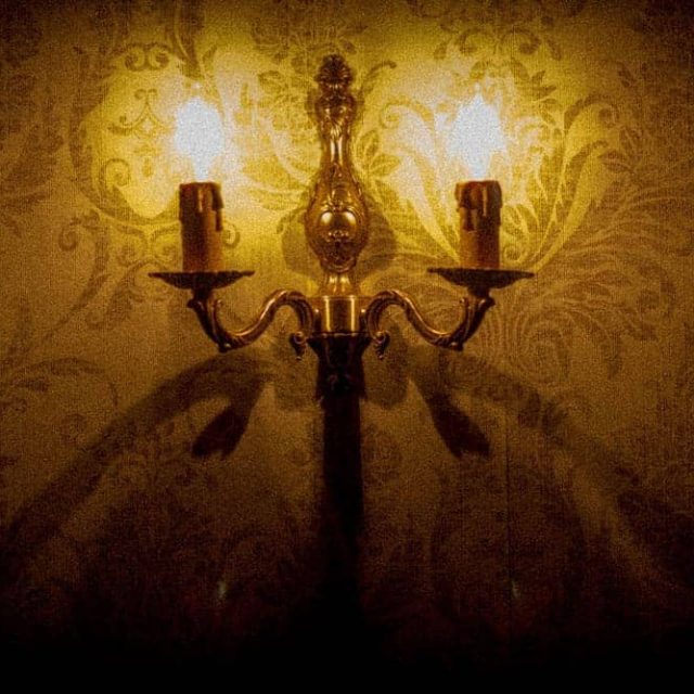 Candélabre en bronze sur papier peint damassé dans Le Manoir des Sœurs Aubépine