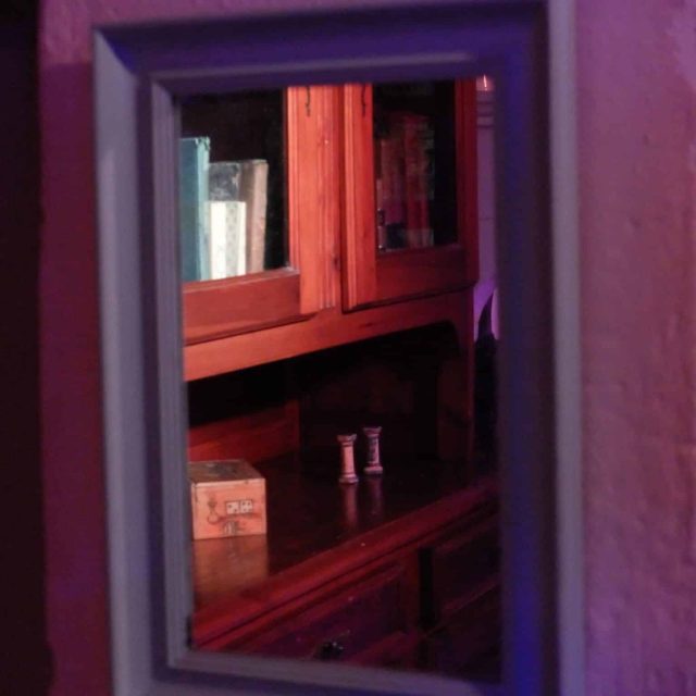 Intérieur rouge et violet avec vitrines et objets énigmatiques au Moulin Hanté