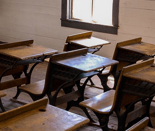 Classe abandonnée avec pupitres anciens, tableau noir et mobilier délabré chez Lazil Escape Game
