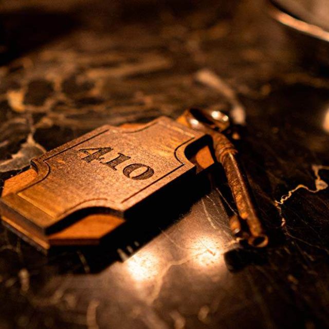 Clé d'hôtel avec porte-clé en laiton sur un comptoir de marbre noir veiné, salle Sunhill Hotel chez Escape Time à Laval