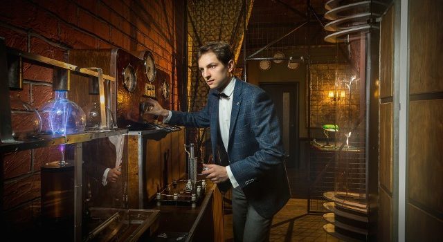 Homme en costume manipulant un appareil lumineux bleu dans un décor de bois et de laiton, Voyage dans le temps