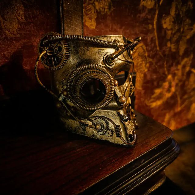 Masque doré mécanique aux rouages posé sur un meuble en bois, salle Le retour de Sherlock Holmes chez Freeing à Osny