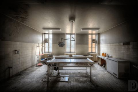 Salle d'opération délabrée avec table centrale et fenêtres, salle Le virus L.R chez Secret escape à Bourgoin-Jallieu