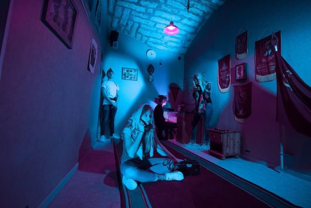 Intérieur aux néons bleus et roses avec figurines et accessoires dans Le mystérieux Vladimir, agent du KGB