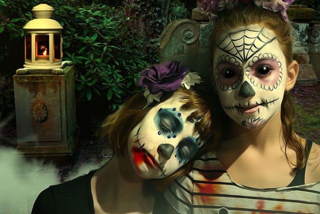 Deux jeunes femmes maquillées en têtes de mort mexicaines près d'une lanterne, salle Dia de Muertos chez Action Réaction