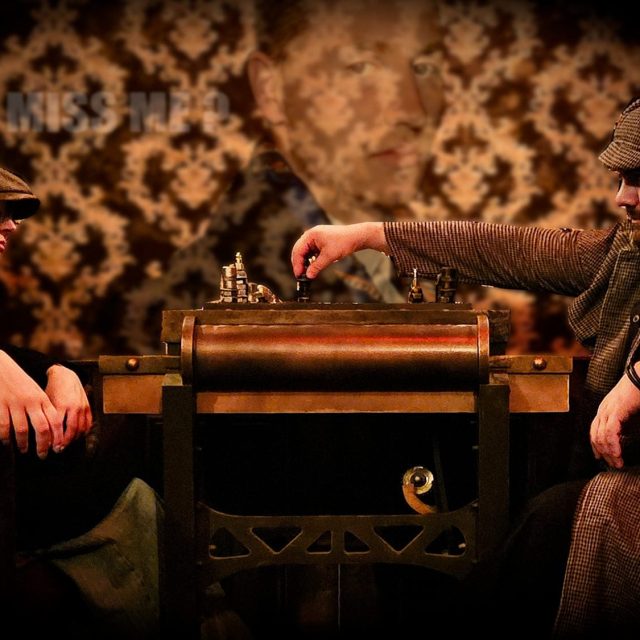 Deux hommes en casquette autour d'un jeu d'échecs mécanique, salle Sherlock Holmes chez Freeing à Saint-Maximin