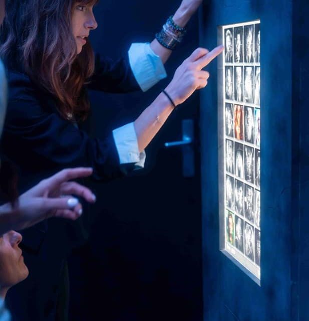 Mains pointant un mur d'images éclairées, jeu de Juma à Mougins
