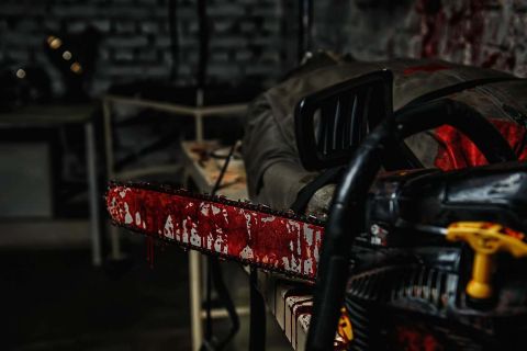 Tronçonneuse tachée de sang dans un décor sombre de bunker, salle Zombie bunker chez Alex K'ape à Caudry