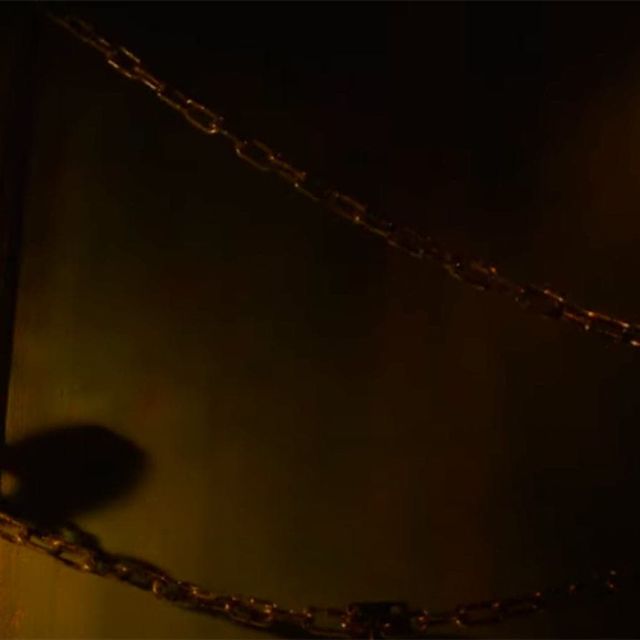 Chaînes suspendues devant un mur sombre jaunâtre, salle La secte chez Freeing à Saint-Maximin