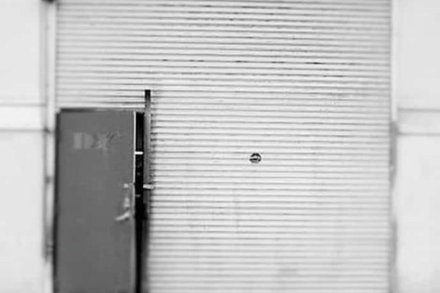 Rideau métallique de garage gris et porte rouge, mot Garage en rouge, salle L'affaire du crime de Roger à Mornant