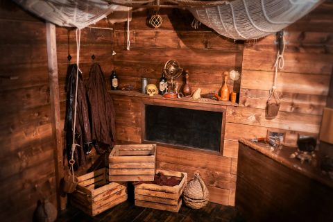 Cabine de pirate avec crâne, bouteilles, filets et coffres en bois dans La malédiction de Francis Drake