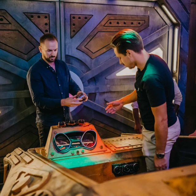 Trois joueurs autour d'une console futuriste dans un décor sci-fi chez Escape from Earth