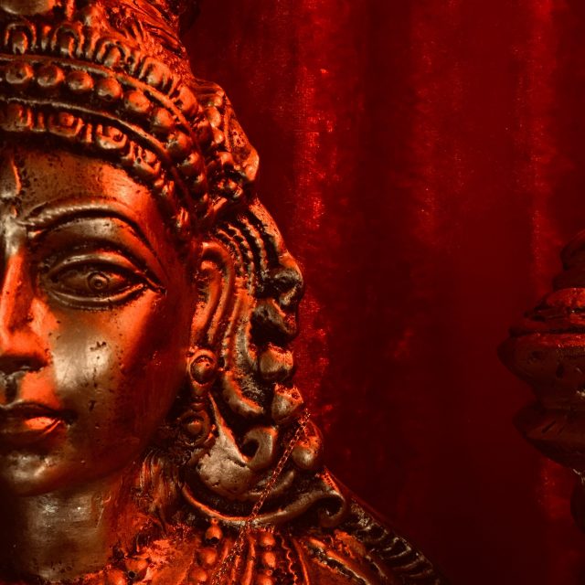 Statue ornementée illuminée en orange et rouge, ambiance mystérieuse dans Indian Trip