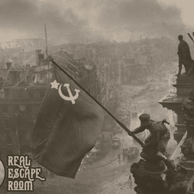 Drapeau soviétique planté sur ruines urbaines, soldats, fumée, décor historique sombre chez Real Escape Room Marseille