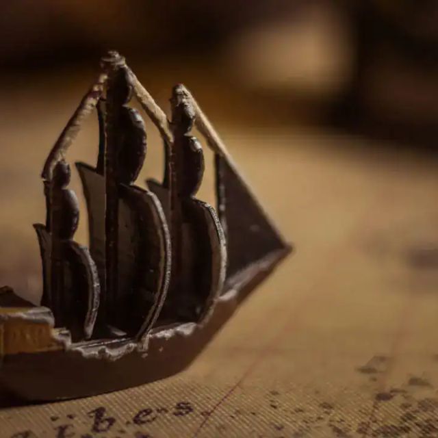 Maquette de voilier posée sur une carte marine ancienne, salle Le Repaire de Rackham