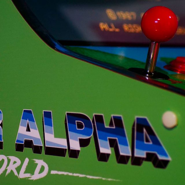 Borne d'arcade verte avec joystick rouge et titre Super Alpha World, salle du même nom chez Escape Time à Angers