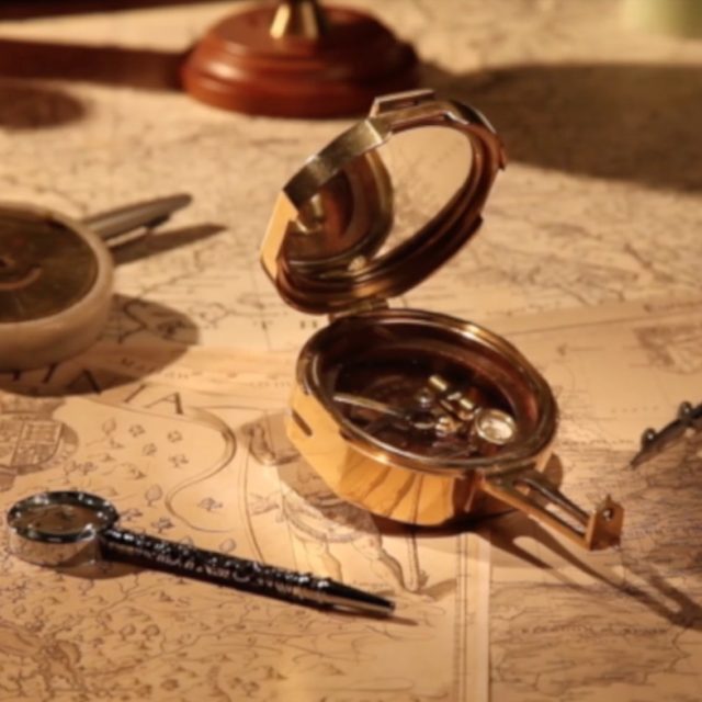 Compas dorés et cartes anciennes sur table poussiéreuse, décor égyptien de L'étrange malédiction du pharaon