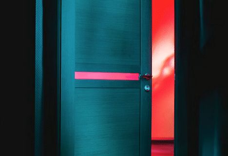 Porte entrouverte bleu-vert laissant filtrer une lumière rouge, salle Hannibal chez Délivrés à Pau